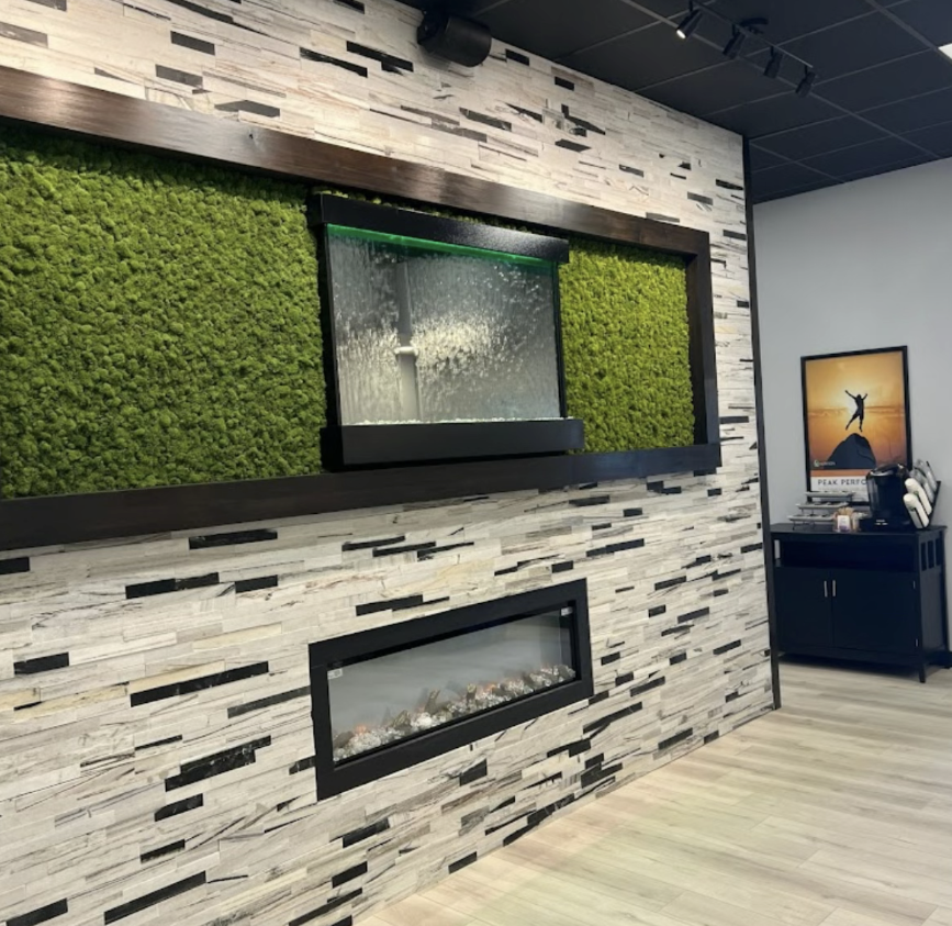 An office with a fireplace and moss on the wall.